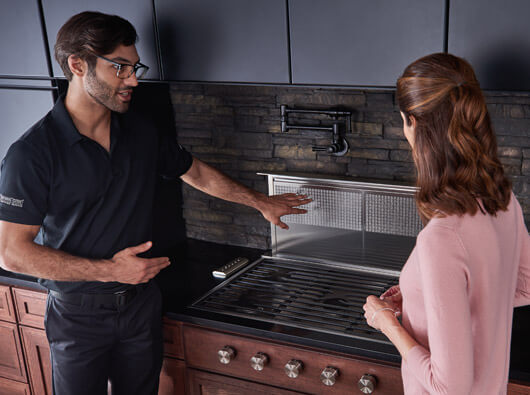 Factory Certified Technician explaining the stovetop filter system to a female client